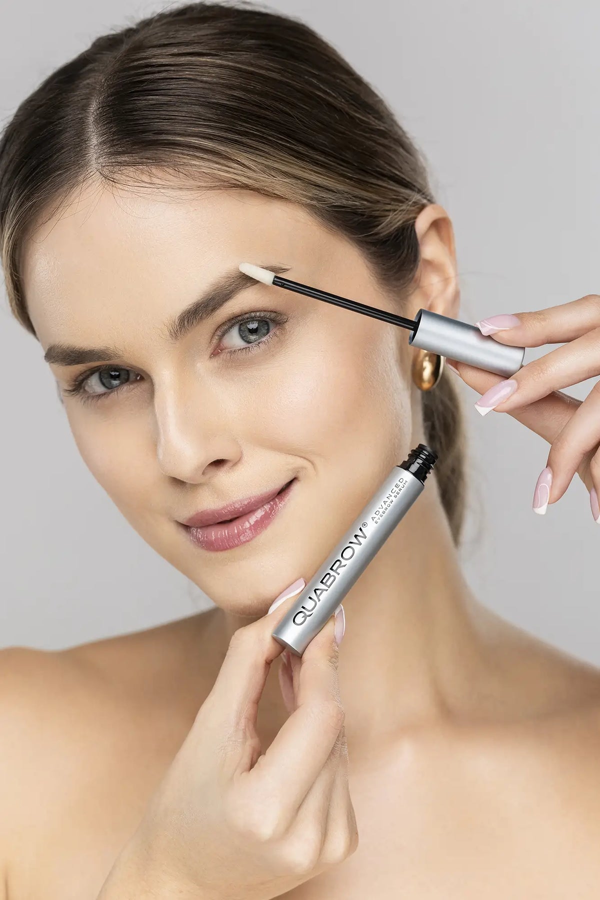 Woman applying QUABROW Advanced Eyebrow Serum to light-colored eyebrows