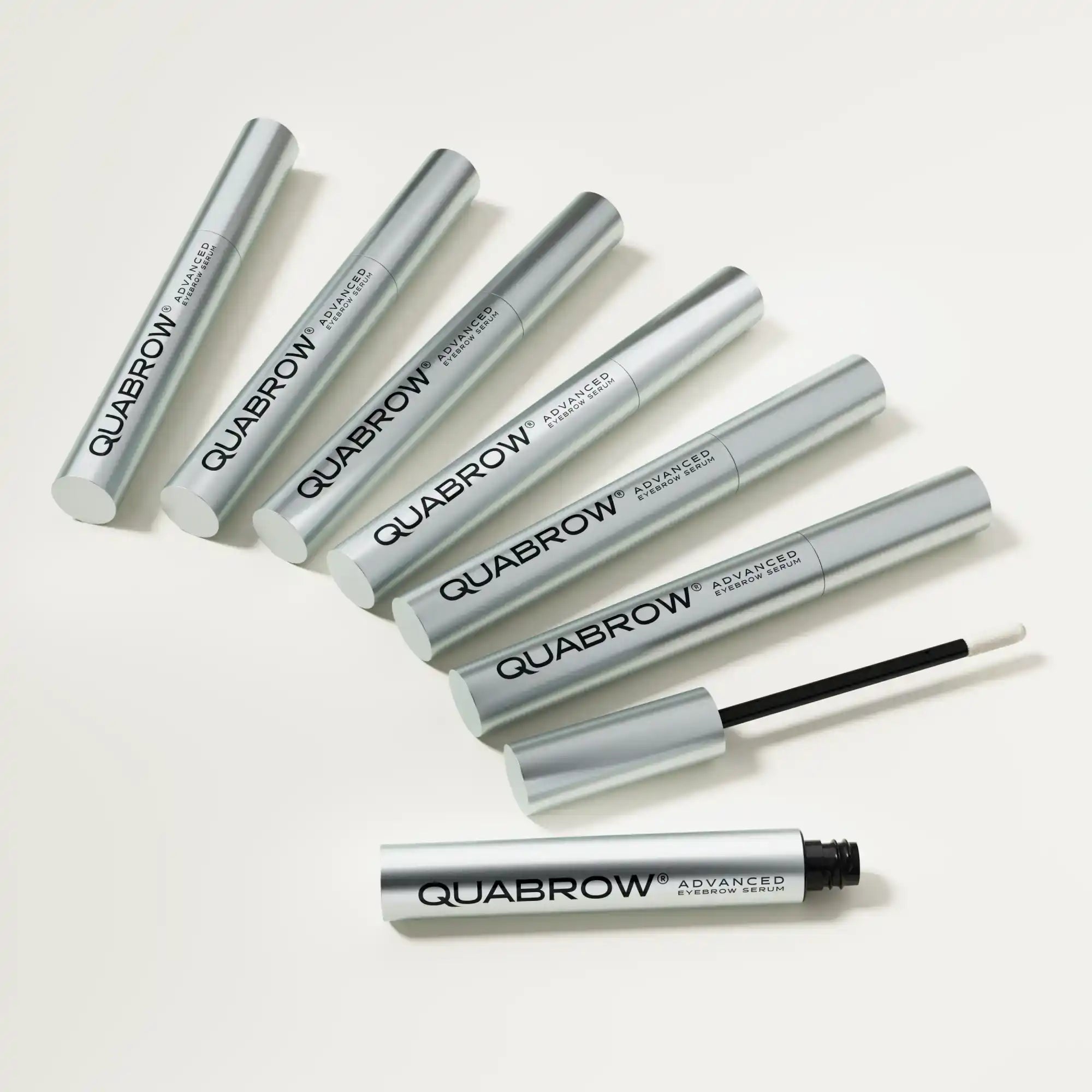 QUABROW Advanced Eyebrow Serum – multiple silver tubes with one open showing applicator