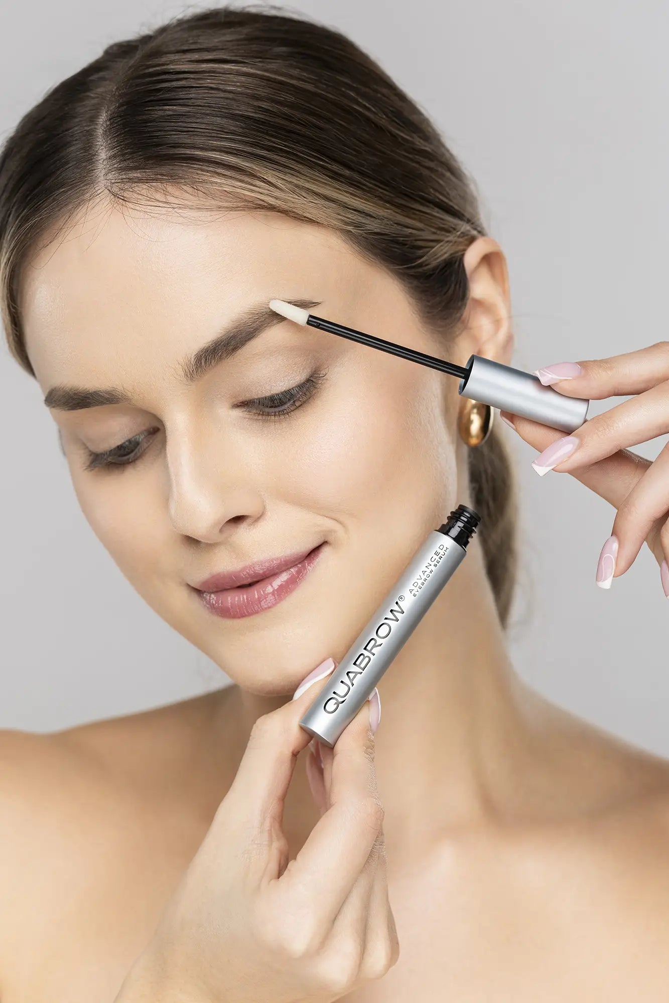 Blonde woman applying QUABROW Advanced Eyebrow Serum to her eyebrows using the applicator – step-by-step use