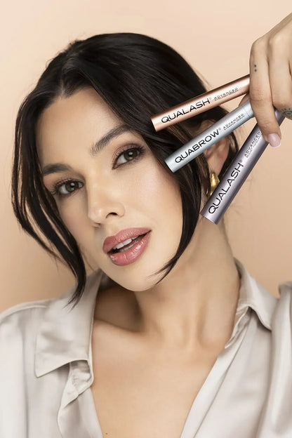 Woman holding three QUALASH serums including QUALASH Mascara, QUABROW Eyebrow Serum and QUALASH Eyelash Serum